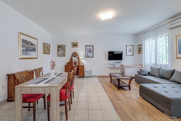 Una sala de estar con comedor, un sofá, un televisor y obras de arte en las paredes.