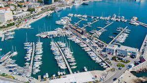 A marina with numerous boats docked in a structured layout, surrounded by buildings and a rocky breakwater. - Beachfront apartment Drazen, with patio & parking (Split)