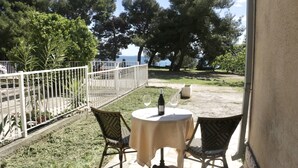 An outdoor patio with two round tables, each with a wine bottle and glass, surrounded by wicker chairs. - Beachfront apartment Drazen, with patio & parking (Split)