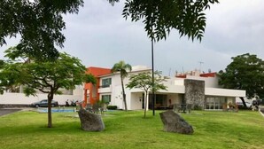 Un edifici modern amb teulada vermella, envoltat d'un jardí ben cuidat i roques grans.