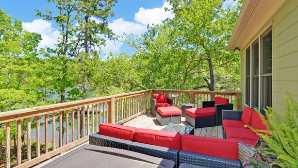 Une terrasse avec des sièges extérieurs, une vue sur un lac et des arbres tout autour.