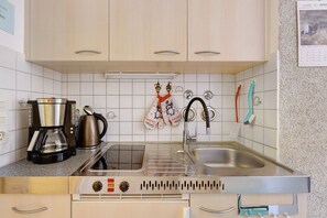 Una cocina equipada con cafetera, hervidor y estufa.
