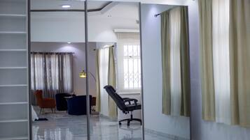 A modern office space with a glass partition, a black office chair, and a blue sofa.