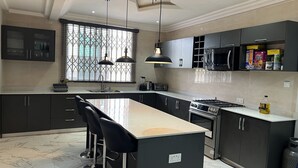 A modern kitchen with dark cabinets, a central island with bar stools, a built-in oven, and a microwave.