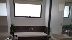 Et moderne badeværelse med badekar, toilet og håndvask.