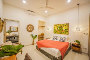 Relax in this serene bedroom with a large bed, ceiling fan, and wall-mounted air conditioner.