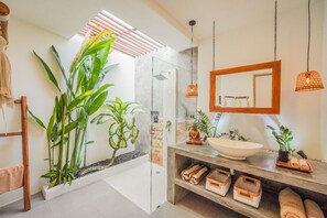 Features a large vessel sink, pendant lights, and a large mirror above a wooden frame.