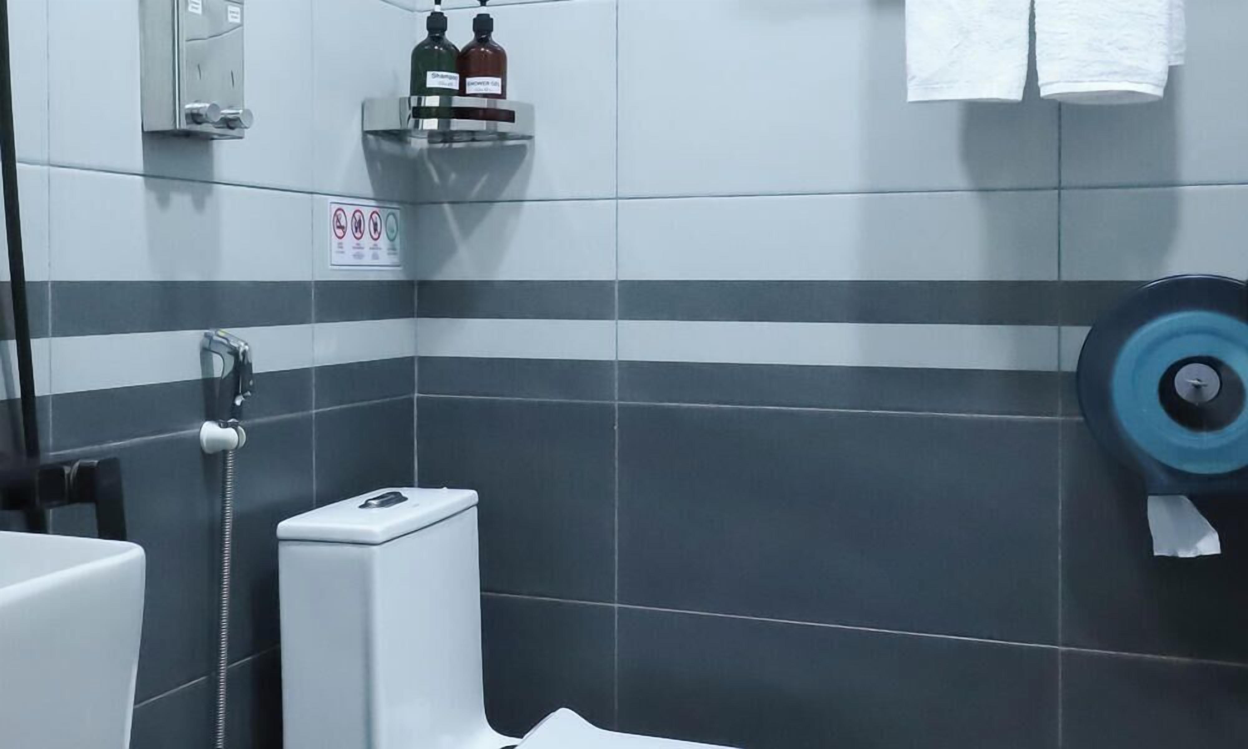 A bathroom with a shower, toilet, and hand dryer.
