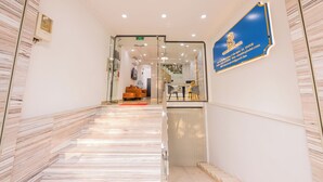 Zona de recepción de un hotel con suelo de mármol, mostrador de recepción y un letrero azul con información del hotel.