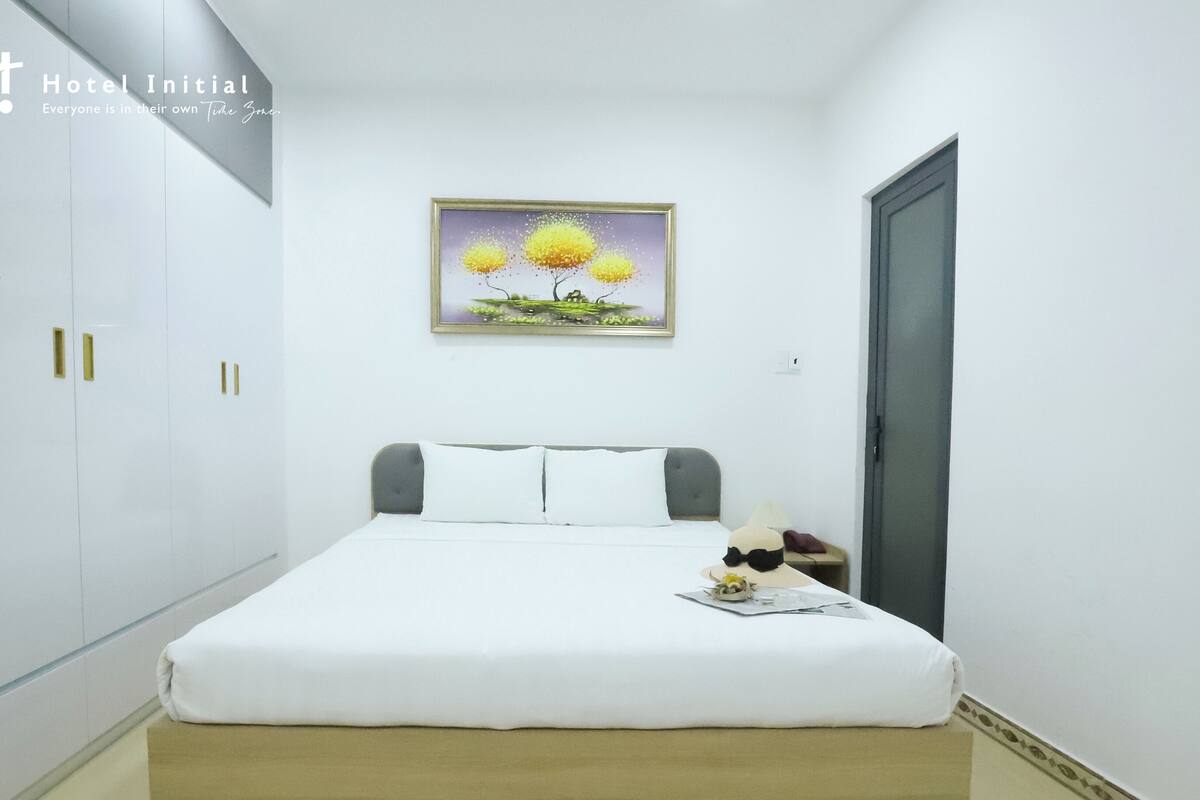 Ein Hotelzimmer mit einem Bett, einem Nachttisch, einem Gemälde und einem Kleiderschrank.