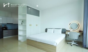 Une chambre d’hôtel moderne équipée d’un lit, d’une table de chevet, d’un miroir et d’un coin cuisine.