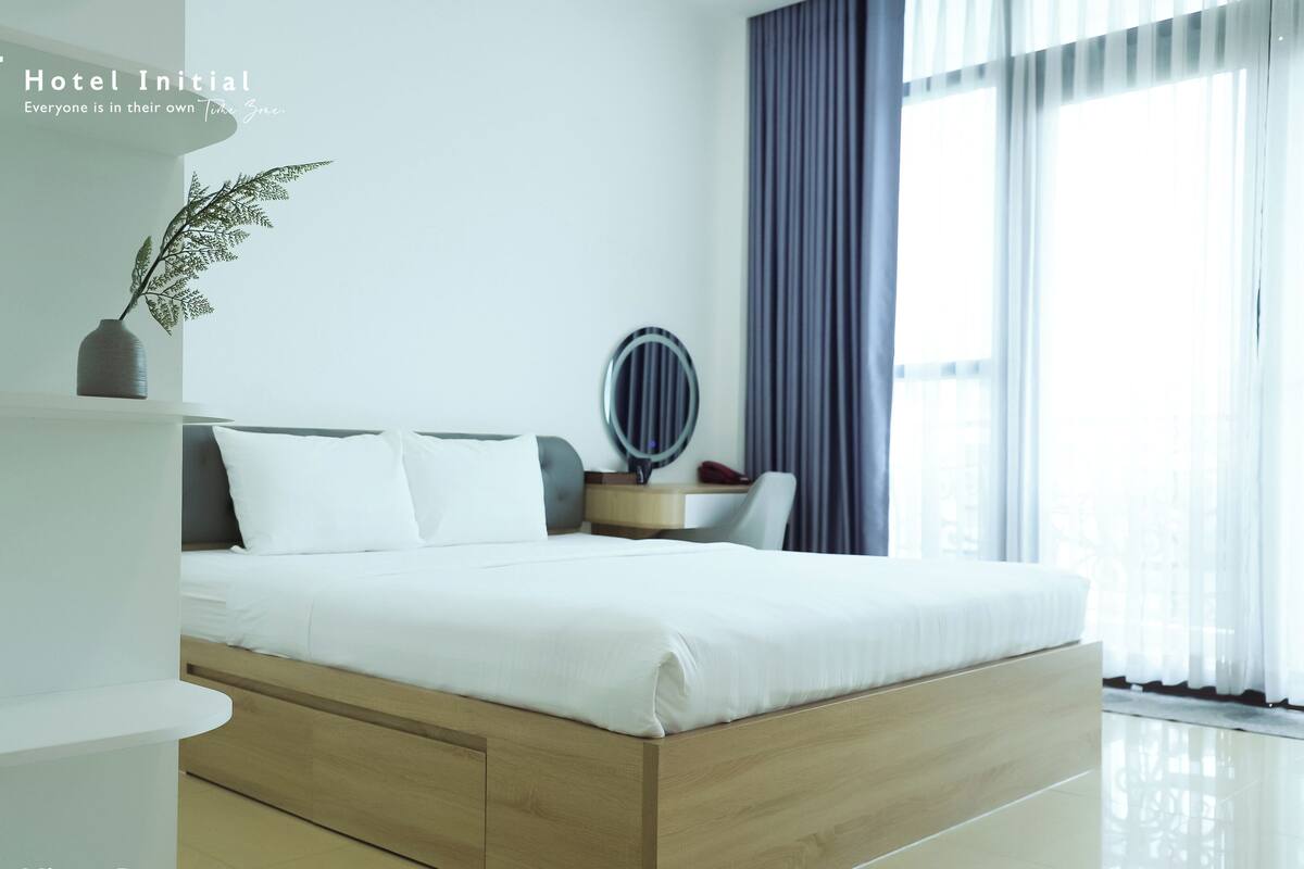 Ein modernes Hotelzimmer mit einem großen Bett, einem Nachttisch mit Spiegel und einer Topfpflanze.