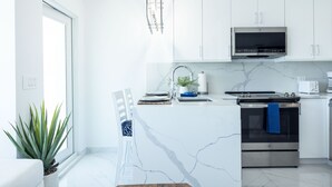 A modern kitchen with white cabinetry, a built-in microwave, and an oven. - Dolphin Suites  (St. John)