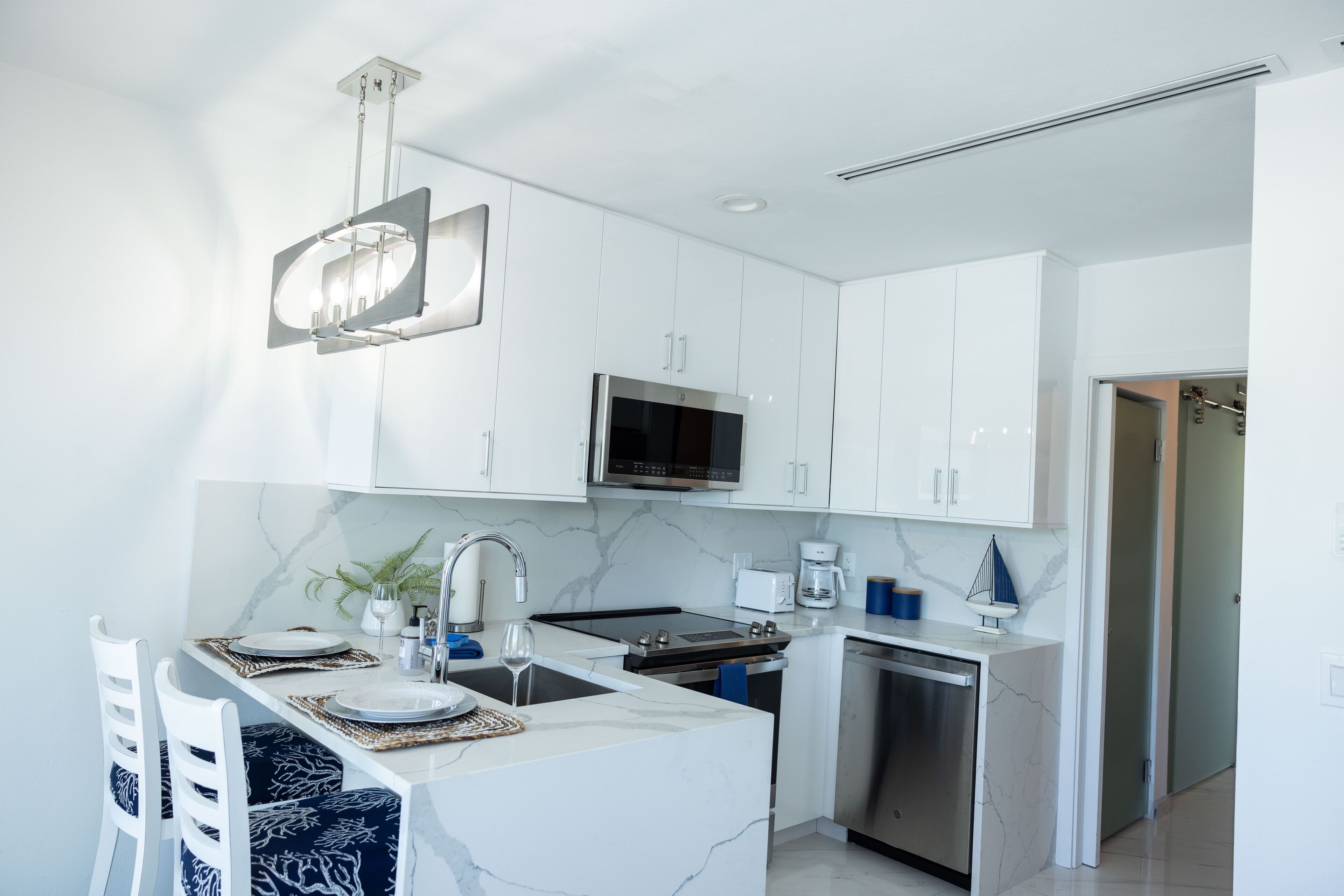 A modern kitchen with white cabinetry, a stainless steel microwave, and a built-in dishwasher.