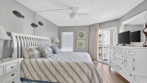 A bedroom with a bed, nightstands, a dresser, a ceiling fan, and artwork on the walls. - Oceanfront Condominium with Great Amenities (Saint Simons Island)
