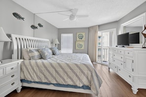 A bedroom with a bed, nightstands, a dresser, a ceiling fan, and artwork on the walls. - Oceanfront Condominium with Great Amenities (Saint Simons Island)