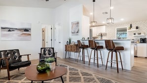 Una sala de estar moderna con una barra para café, sillones de cuero y una zona de comedor con una mesa redonda.