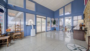 A spacious lobby with large windows, a reception desk, and several chairs. - Cannon Inn By Capital O Gonzales Tx (Gonzales)