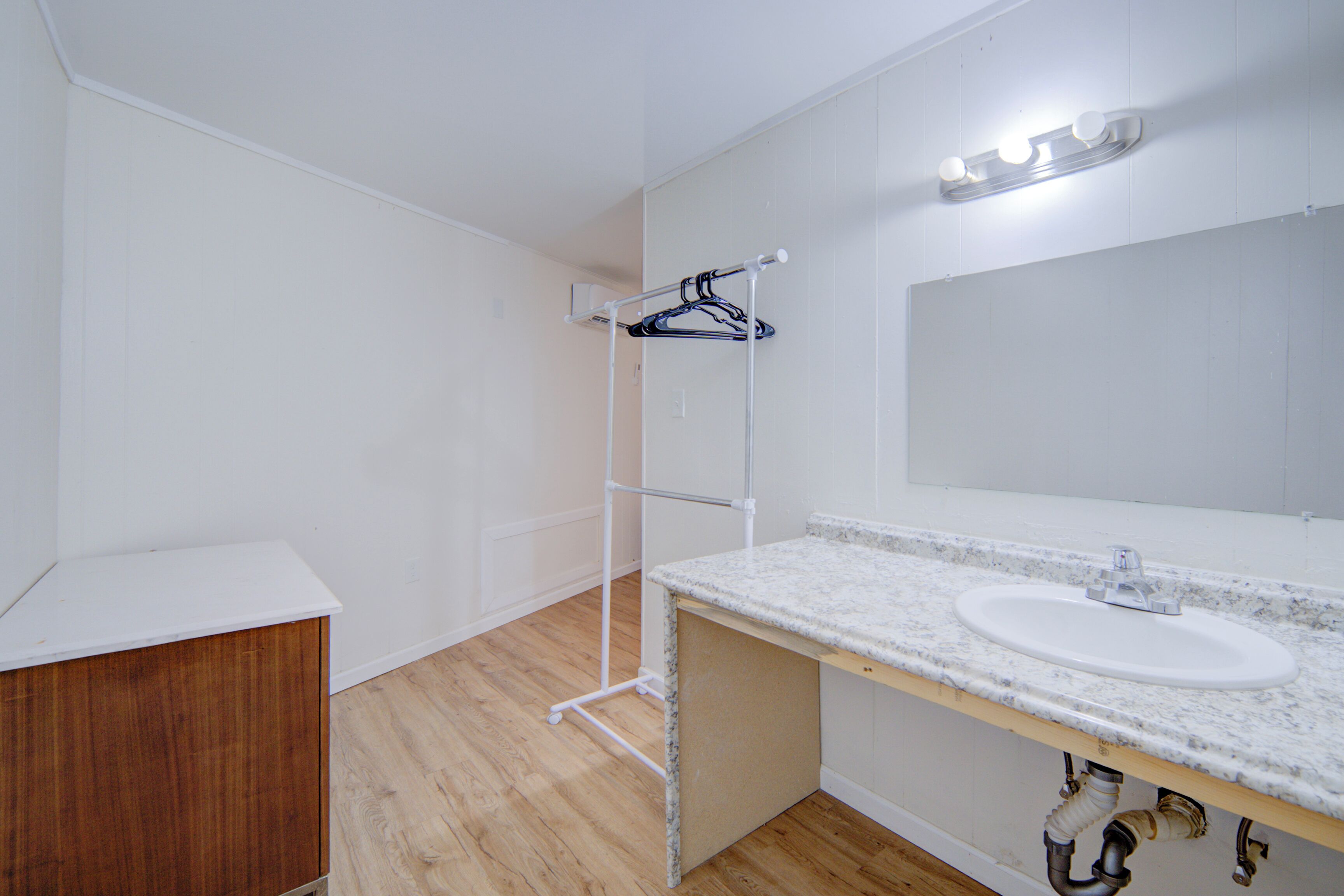 A bathroom with a white sink, wooden cabinet, and a towel rack.