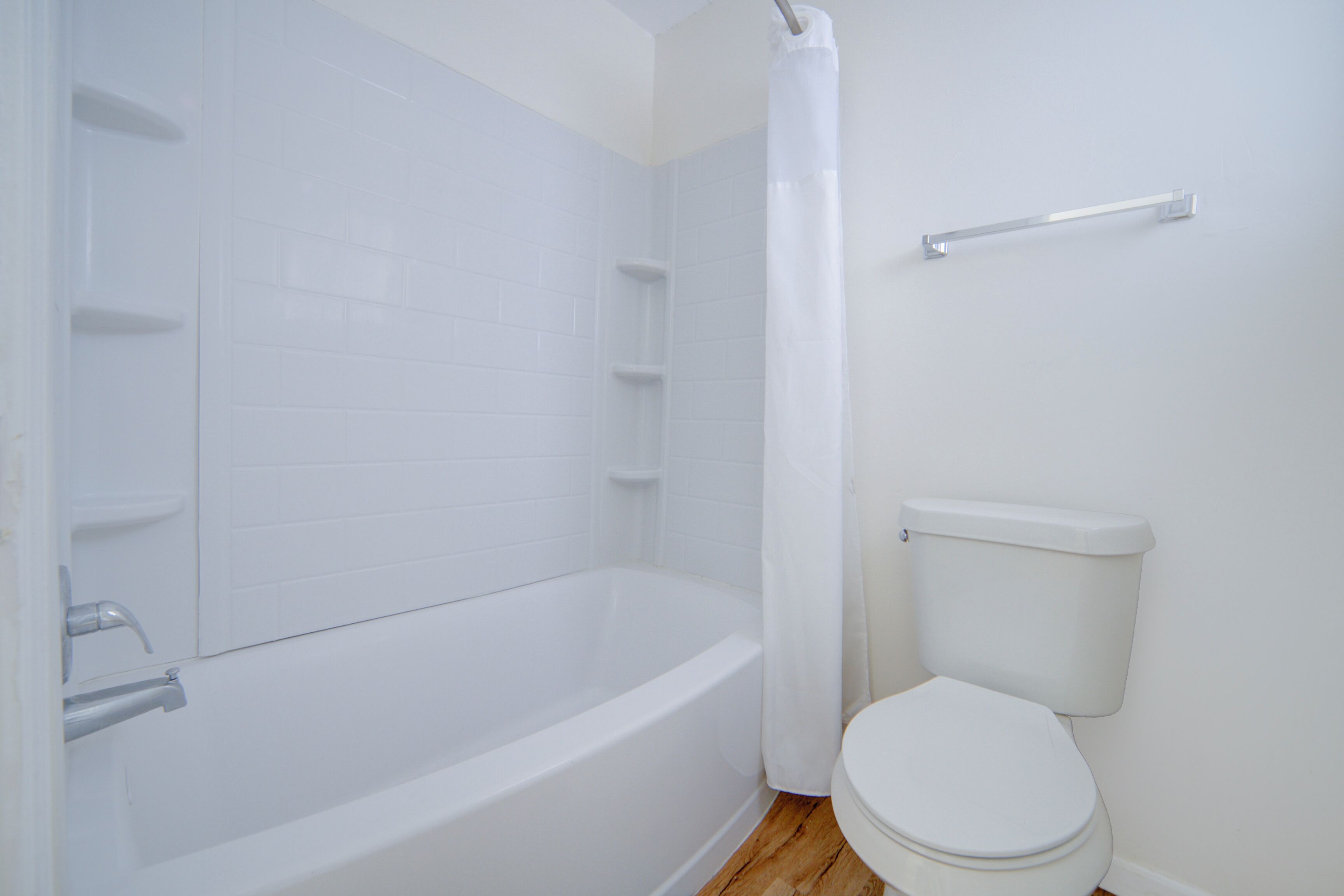 Bagno con vasca da bagno bianca, un water e una tenda da doccia.