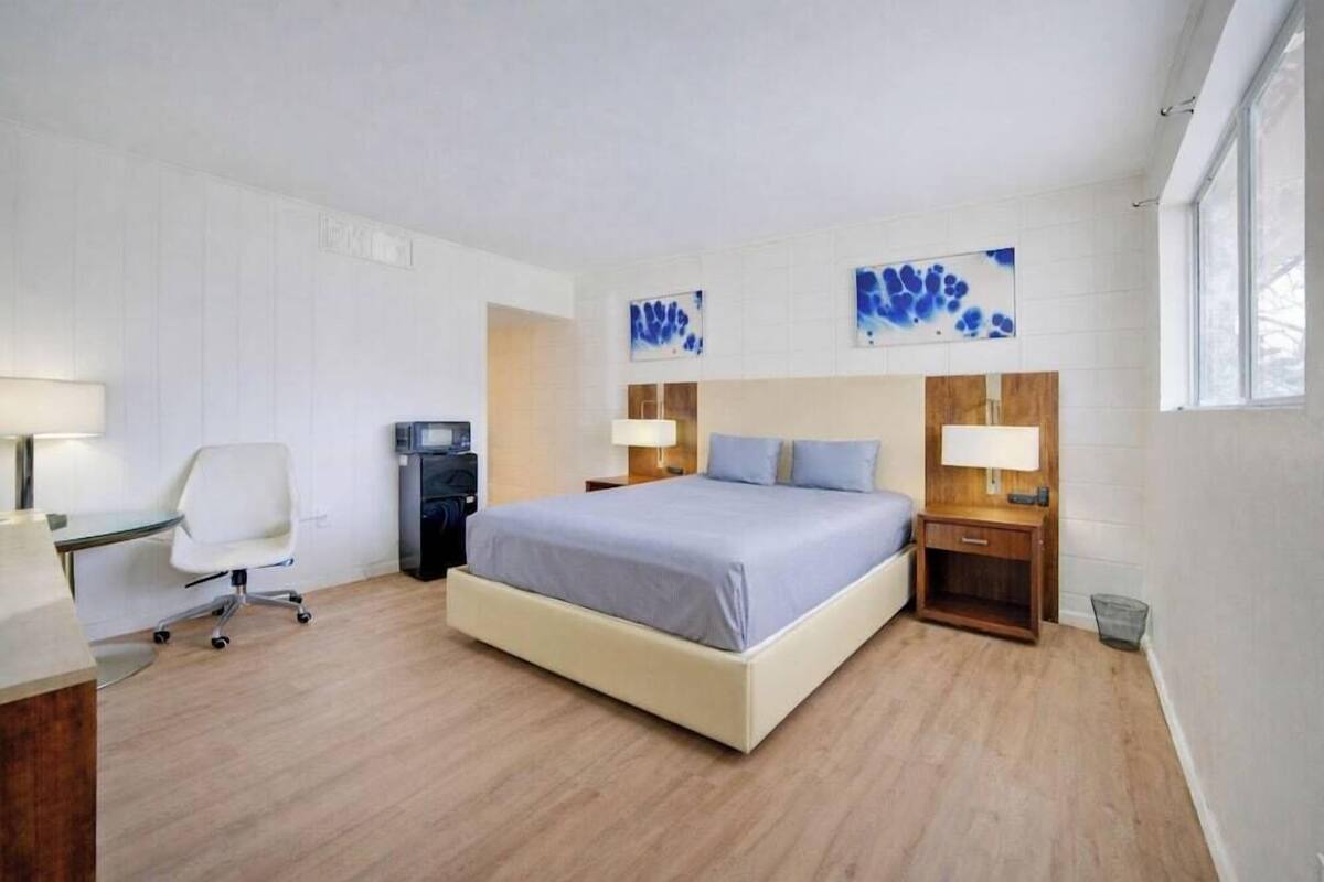 A modern bedroom with a bed, bedside tables, a desk, and a chair.