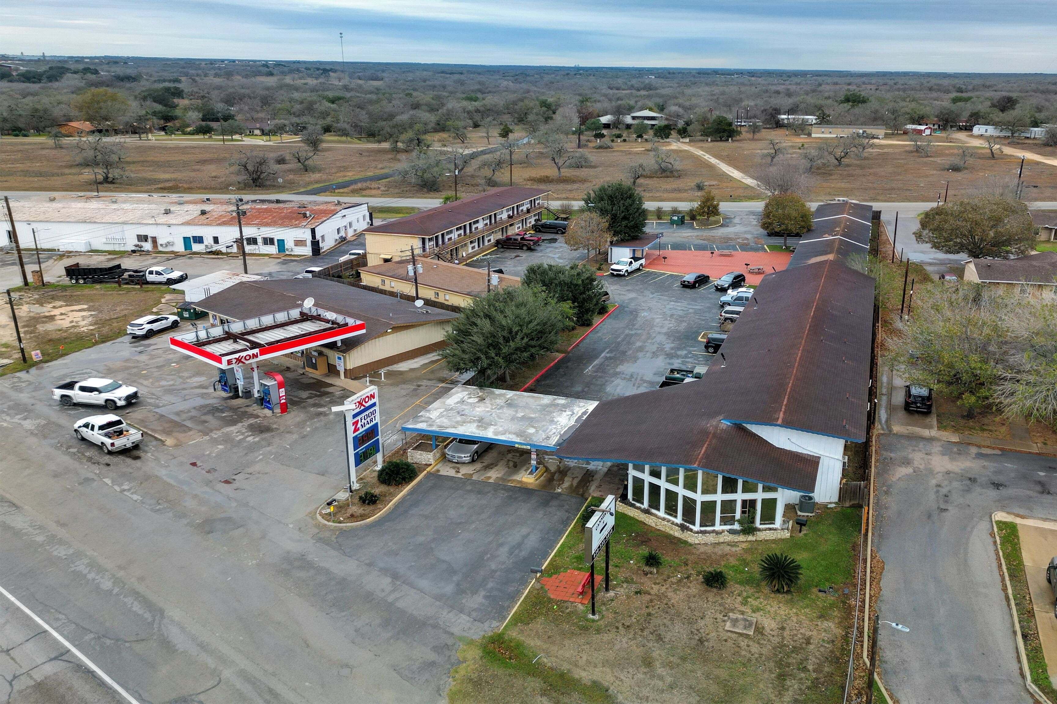 Vista aérea de una zona comercial que incluye una gasolinera, un motel y algunos edificios.
