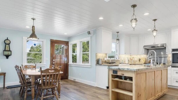 A spacious kitchen with wooden cabinetry, a central island, and pendant lighting. - Butterfly Beach House (Santa Cruz)