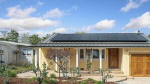 A single-story house with a dark roof, a front porch, and a garage. - Butterfly Beach House (Santa Cruz)
