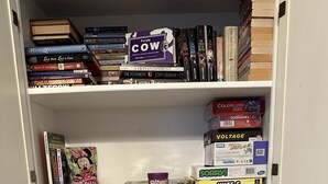 Una estantería con varios libros y juegos de mesa.