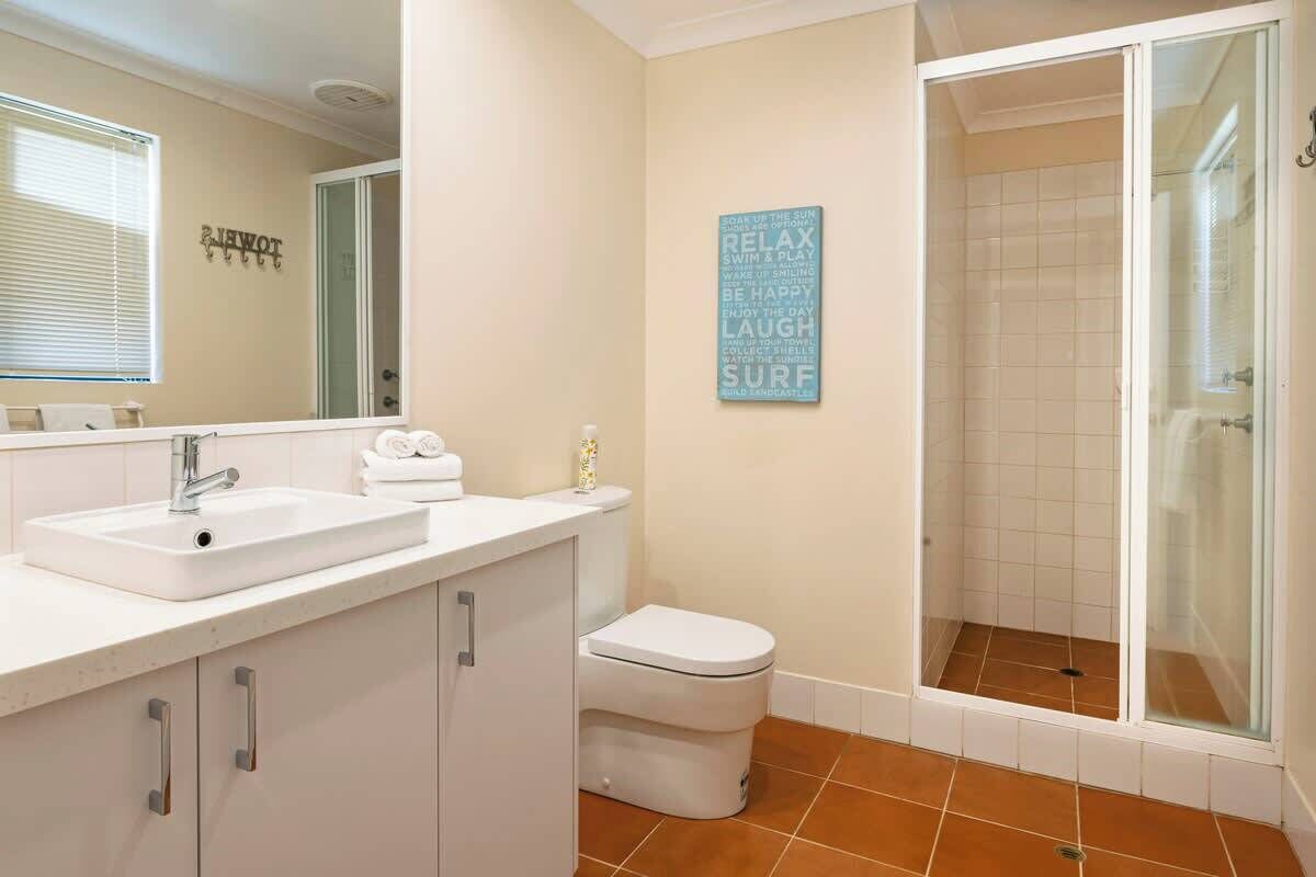 A bathroom with a sink, toilet, and shower area.