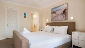 Una camera da letto con un letto grande, un comodino, una porta e un quadro appeso al muro.