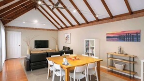 Zona pranzo con tavolo e sedie in legno, un divano, una libreria e un quadro appeso al muro.