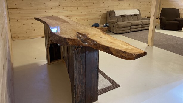 A room with wooden walls, a large wooden table, a sofa, and a chair.