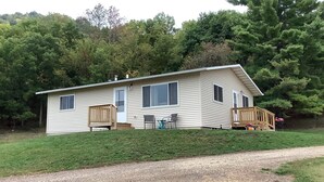 A single-story house with a front porch, a small deck, and a gravel driveway.