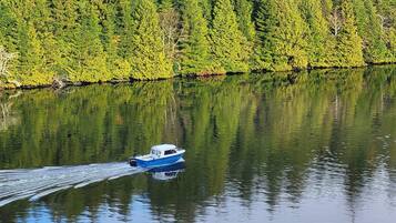 A boat moving across a calm lake surrounded by dense forest.
