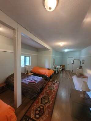 A compact room with two beds, a small table, a chair, and a desk. - Argo's Landing (Bamfield)