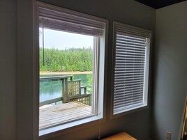 Una habitación con dos ventanas que dan a un lago y un bosque.