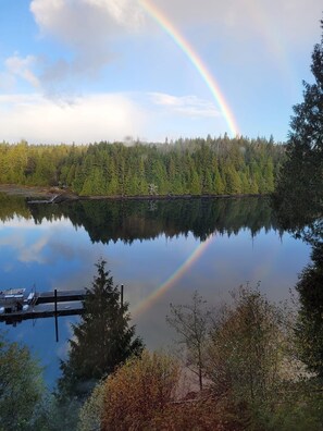 A calm lake with a rainbow, dock, and forested shoreline. - Argo's Landing (Bamfield)