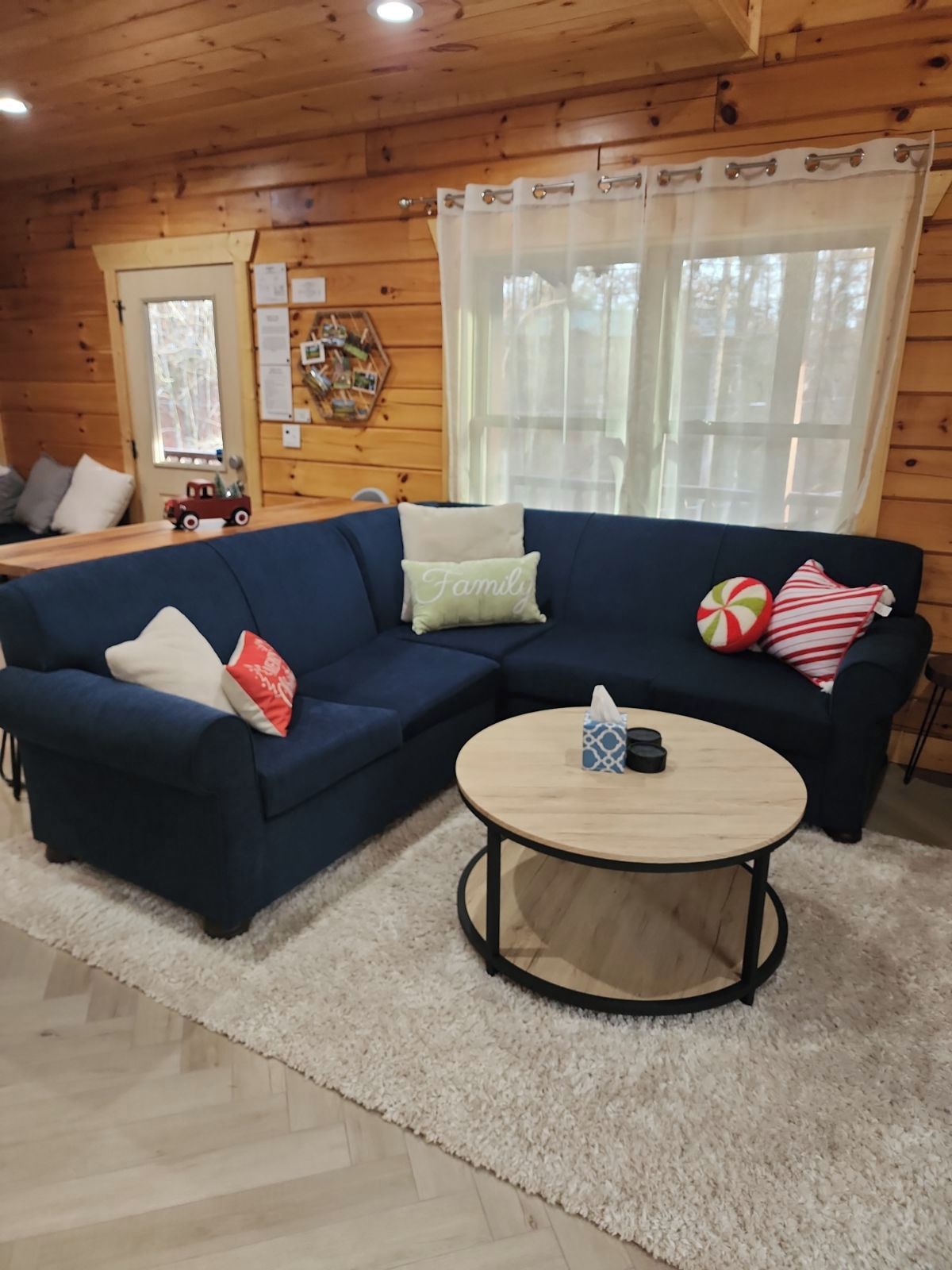 Un ambiente accogliente con un divano blu componibile, un tavolino rotondo in legno e un tappeto bianco e soffice.