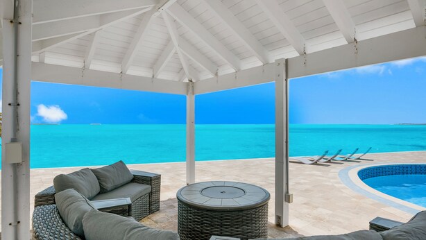 A covered outdoor seating area with a view of the ocean, a pool, and lounge chairs. - Ocean Front Property With Pool. - George Town (Exuma)