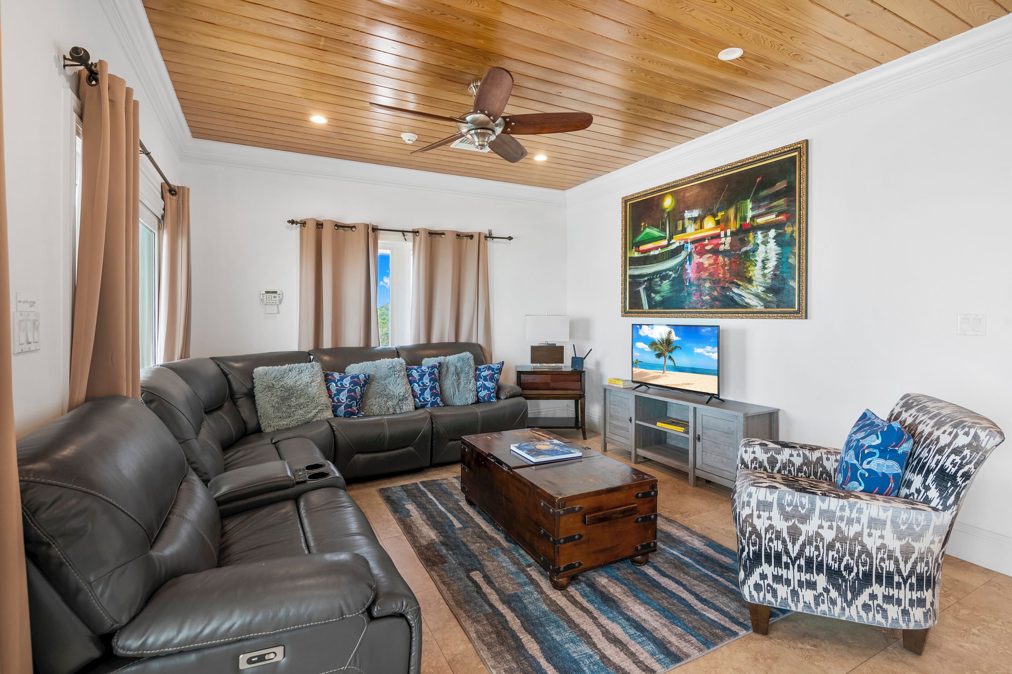 A living room with a sofa, a patterned armchair, a wooden coffee table, and a ceiling fan.