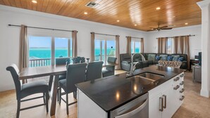 A spacious kitchen with a large island, dining area with chairs, and a view of the ocean. - Ocean Front Property With Pool. - George Town (Exuma)