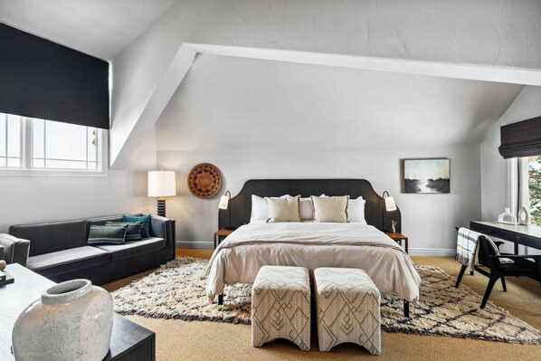 Ein Schlafzimmer mit Bett, Nachttischen, Schreibtisch, Stuhl, Sofa und Teppich.