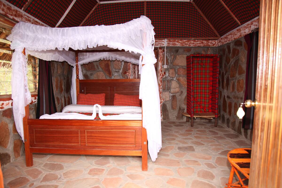 A four-poster canopy bed with a stone floor and a stone wall backdrop.