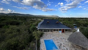 Una casa con piscina de piedra y techo de paja.