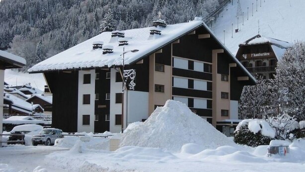 Un edificio cubierto de nieve con una pista de esquí al fondo.