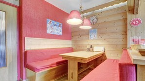 Una habitación acogedora con paredes de madera y un banco rojo. Hay una mesa de madera con una lámpara encima.