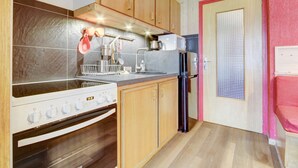 Una cocina compacta con armarios de madera, horno empotrado, refrigerador y microondas.