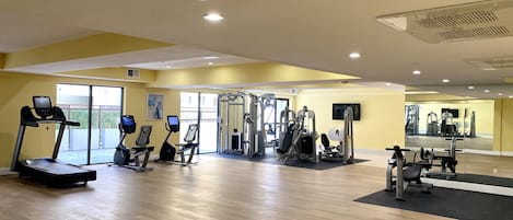 Une salle de sport équipée de tapis de course, de vélos elliptiques et d’appareils de musculation.