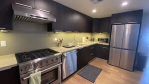 A modern kitchen with dark cabinetry, stainless steel appliances, a gas stove, a dishwasher, and a microwave.